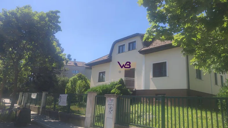 Fassade eines Einfamilienhauses mit gepflegtem Vorgarten und klarem Himmel an einem sonnigen Tag.