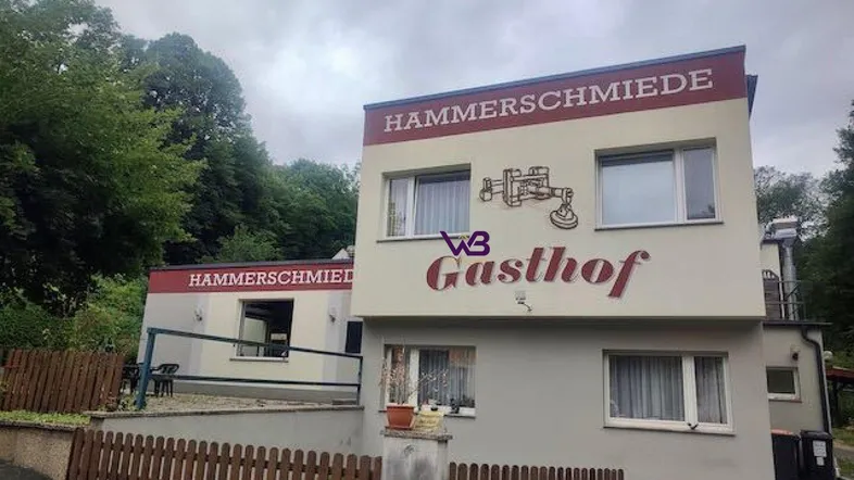 Gebäude der Hammerschmiede Gasthof mit schlichter Fassade und umgebender Natur.