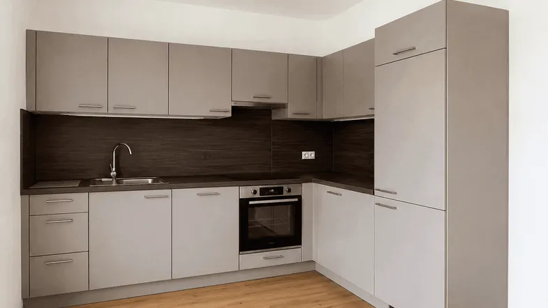 Moderne Einbauküche in Grau mit integriertem Backofen und Laminatboden.