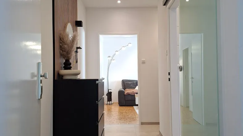 Moderner Flur mit Einbauschrank, Einbaustrahlern und hellem Fliesenboden.