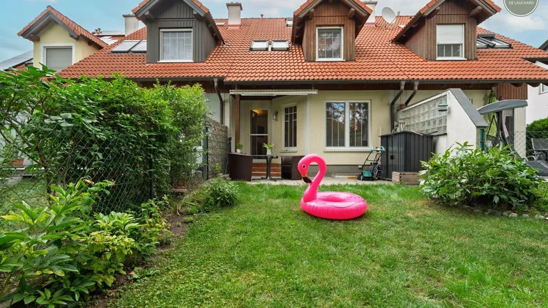 Gepflegter Gartenbereich mit Rasenfläche, Terrasse und Blick auf die Reihenhäuser.