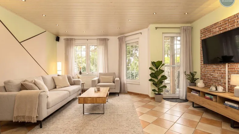 Helles Wohnzimmer mit Fliesenboden, gemütlichem Sofa und modernem Wanddesign.