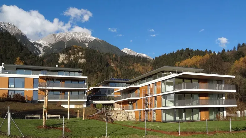Moderne Wohngebäude mit großen Balkonen und beeindruckendem Blick auf die schneebedeckten Berge.