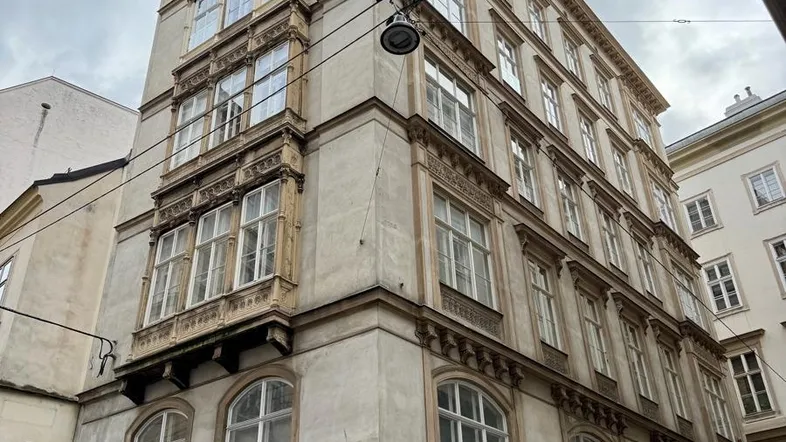 Historisches Mehrfamilienhaus mit klassischer Fassade und Geschäften im Erdgeschoss in einer städtischen Umgebung.
