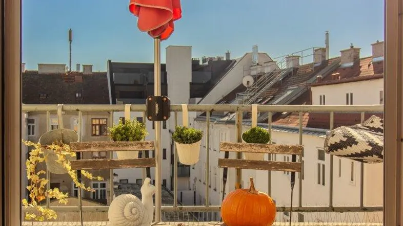 Sonniger Balkon mit kleinem Tisch, Stühlen und Blick auf die umliegenden Gebäude.