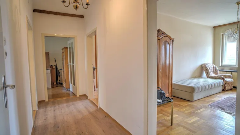 Heller Flur mit Holzboden und Zugang zu verschiedenen Zimmern, ausgestattet mit einem Kronleuchter.