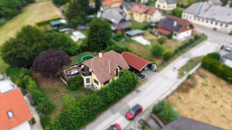 Luftaufnahme eines Einfamilienhauses mit Garten und umliegender Wohnbebauung in ländlicher Umgebung.