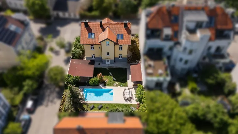 Luftaufnahme des Anwesens mit großem Garten, Pool und umliegender Bebauung.