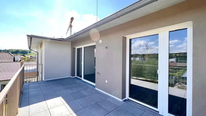 Große, sonnige Terrasse mit modernen Fliesen und Zugang zu den Innenräumen, ideal für Entspannung im Freien.