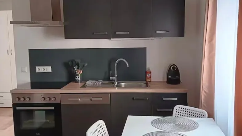 Moderne Küche mit dunklen Schränken, Holzarbeitsplatte und Essbereich für zwei Personen.