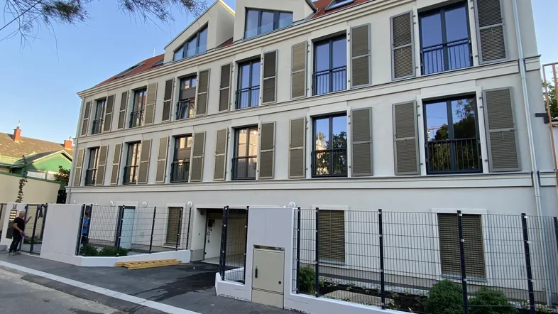 Modernes Mehrfamilienhaus mit vielen Fenstern und Fensterläden in ruhiger Lage.