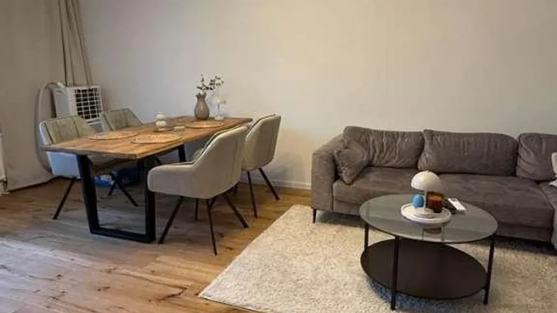 Geräumiger Wohn- und Essbereich mit hellem Holzboden, bequemer Couch und modernem Esstisch.