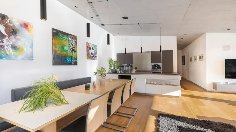 Moderner Essbereich mit Holztisch und integrierter Küche in hellem Design.
