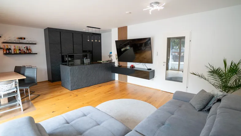 Geräumiger Wohnbereich mit bequemer Couch, moderner Küche und Zugang zum Außenbereich.