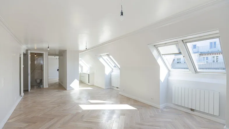 Helles, geräumiges Zimmer mit Fischgrätparkett und Dachfenstern, das viel Tageslicht hereinlässt.