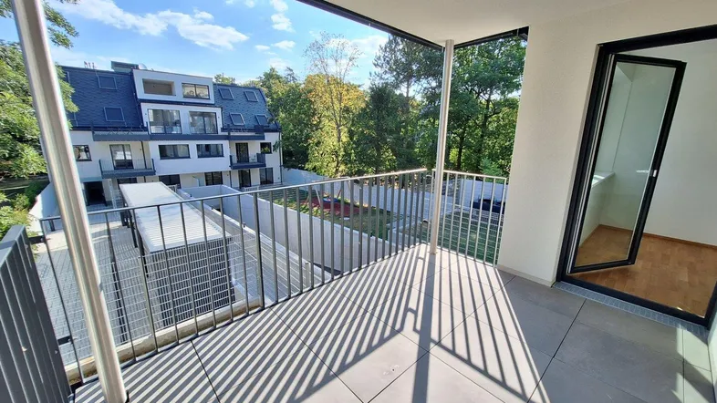 Heller Balkon mit Fliesenboden und Blick auf die umliegende Wohnbebauung und Grünflächen.