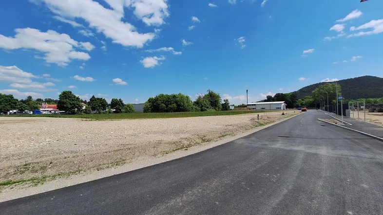 Weitläufiges unbebautes Grundstück mit neu angelegter Straße und Blick auf die umliegende Landschaft.