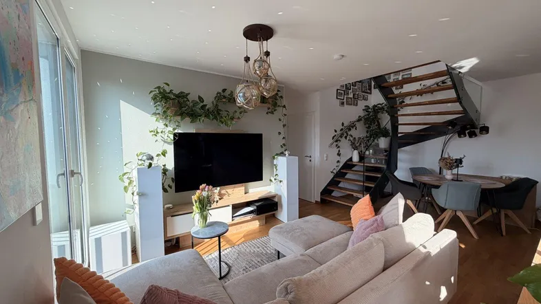 Helles, offenes Wohn- und Esszimmer mit moderner Einrichtung, Pflanzen und einer eleganten Wendeltreppe.