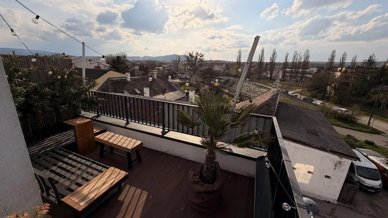Geräumige Dachterrasse mit Holzbelag, Sitzgelegenheiten und Panoramablick über die Stadt.