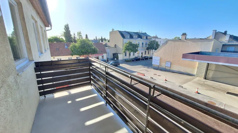 Geräumiger Balkon mit Metallgeländer und Blick auf die umliegende Wohngegend unter blauem Himmel.