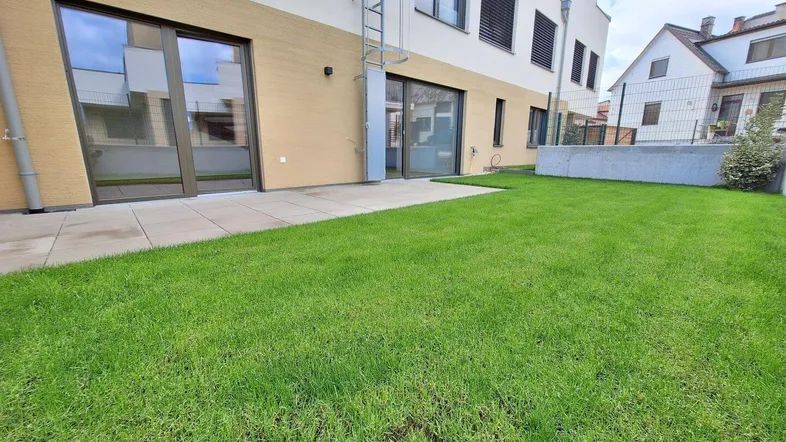 Gepflegter Gartenbereich mit Rasenfläche und angrenzender Terrasse am Neubau.