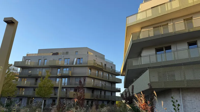 Moderne Wohngebäude mit mehreren Balkonen und ansprechender Landschaftsgestaltung im Vordergrund.