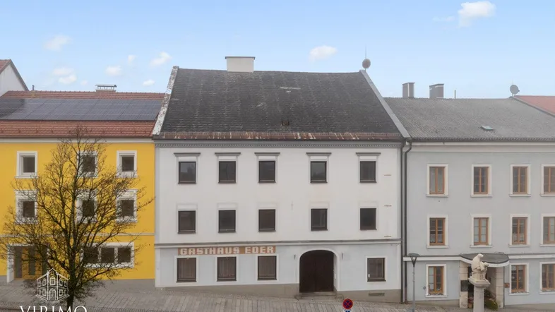 Historisches Gebäude mit traditioneller Architektur und Gasthaus-Beschriftung in einer Stadtansicht.