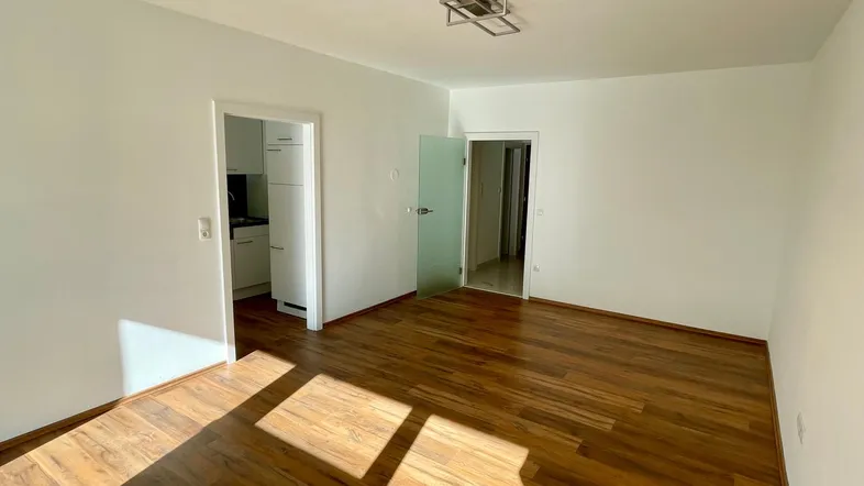 Helles Zimmer mit Holzboden und weißen Wänden, bereit zur individuellen Gestaltung.