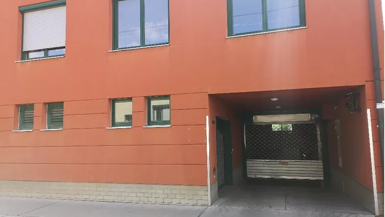 Moderne Fassade eines Wohngebäudes mit orangefarbenem Anstrich und integrierter Garageneinfahrt.