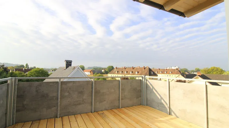 Geräumiger Balkon mit Holzboden und moderner Brüstung, bietet einen weiten Blick über die Umgebung.