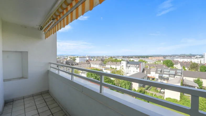 Geräumiger Balkon mit Markise und weitem Blick über die Stadt und die umliegende Landschaft.