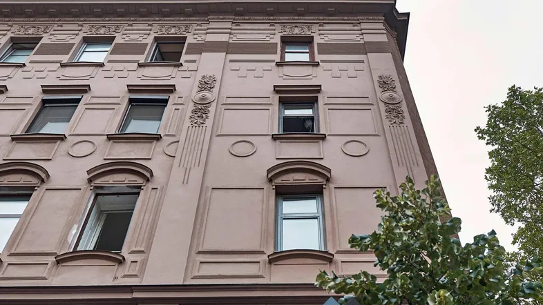 Historische Fassade eines Altbaus mit dekorativen Elementen und mehreren Fenstern.