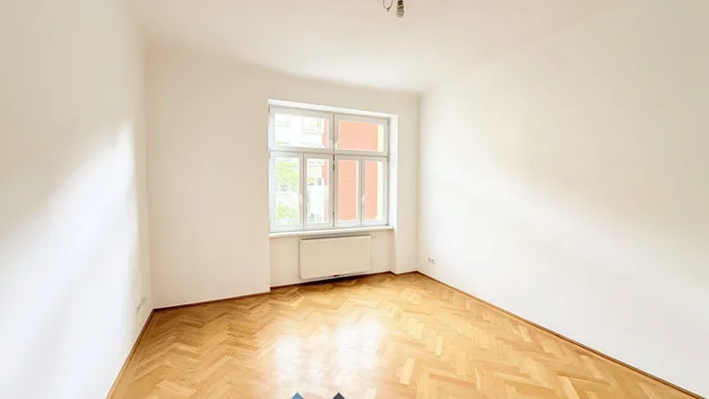 Helles Zimmer mit Fischgrätparkett und weißen Wänden, ideal als Wohn- oder Schlafzimmer.