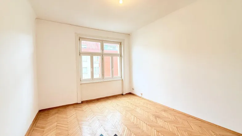 Helles Zimmer mit Fischgrätparkett und weißen Wänden, ideal als Wohn- oder Schlafzimmer.