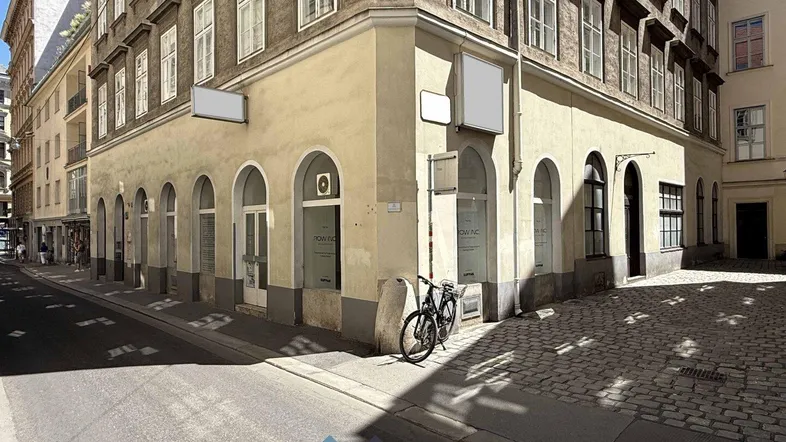 Historisches Eckgebäude mit gewölbten Fenstern und einer belebten Straße in der Stadt.