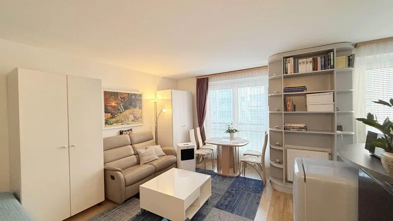Helles Wohnzimmer mit Sofa, Esstisch und integriertem Schlafbereich, ausgestattet mit modernen Möbeln.