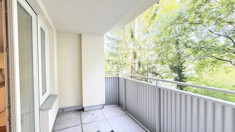 Heller Balkon mit Fliesenboden und Blick ins Grüne, ideal für entspannte Stunden im Freien.