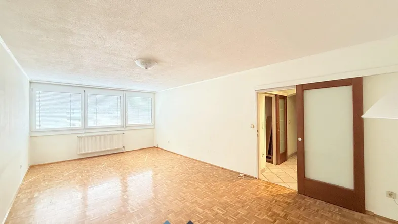 Helles Wohnzimmer mit Parkettboden und großen Fenstern, bereit zur individuellen Gestaltung.