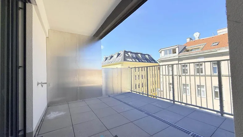Heller Balkon mit Fliesenboden und Blick auf die umliegenden Gebäude der Stadt.