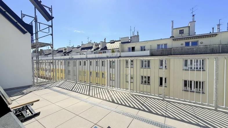 Geräumige Dachterrasse mit Fliesenboden und Blick auf die umliegenden Gebäude.