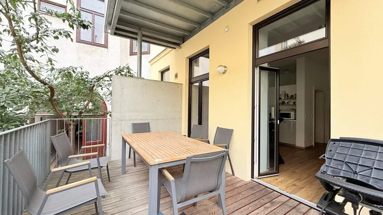 Geräumige Terrasse mit Holzboden, Esstisch und Zugang zum Innenbereich, ideal für Mahlzeiten im Freien.