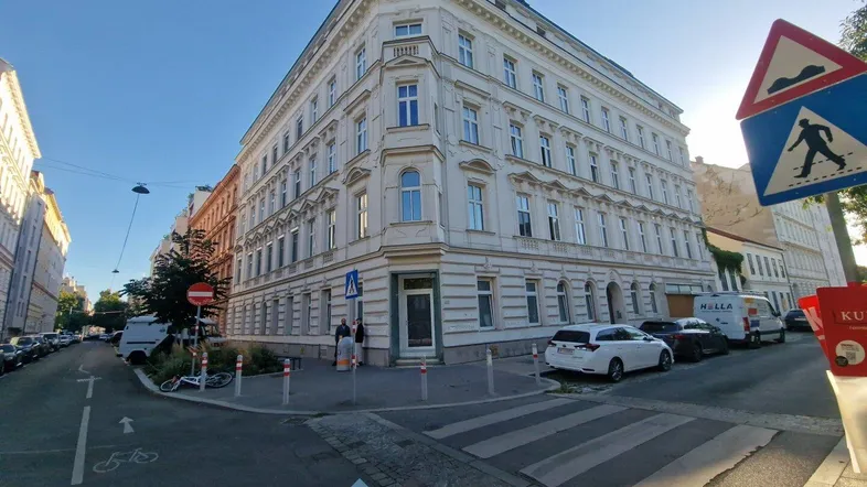 Historisches Eckgebäude in städtischer Umgebung mit klassischer Architektur und Blick auf die Straße.