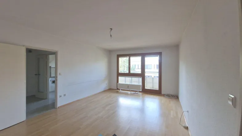 Helles, leeres Zimmer mit Parkettboden und Zugang zu einem Balkon, bereit zur Gestaltung.