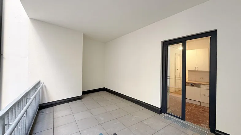 Geräumige Loggia mit Fliesenboden und Zugang zur Küche, ideal für entspannte Stunden im Freien.