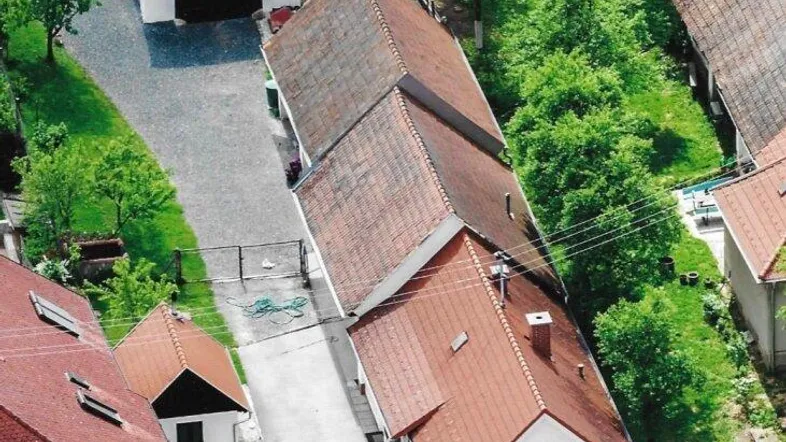 Luftaufnahme eines ländlichen Anwesens mit mehreren Gebäuden, Zufahrt und viel Grünfläche.