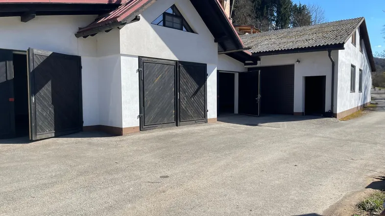 Mehrere Garagen und eine Zufahrt zu einem Gebäude mit ländlicher Umgebung unter blauem Himmel.