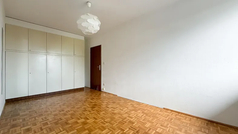 Helles Zimmer mit Parkettboden und praktischen Einbauschränken, ideal als Schlafzimmer oder Büro.