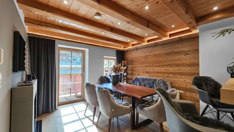 Gemütlicher Essbereich mit Holzbalkendecke, Holzwandverkleidung und Zugang zum Balkon.