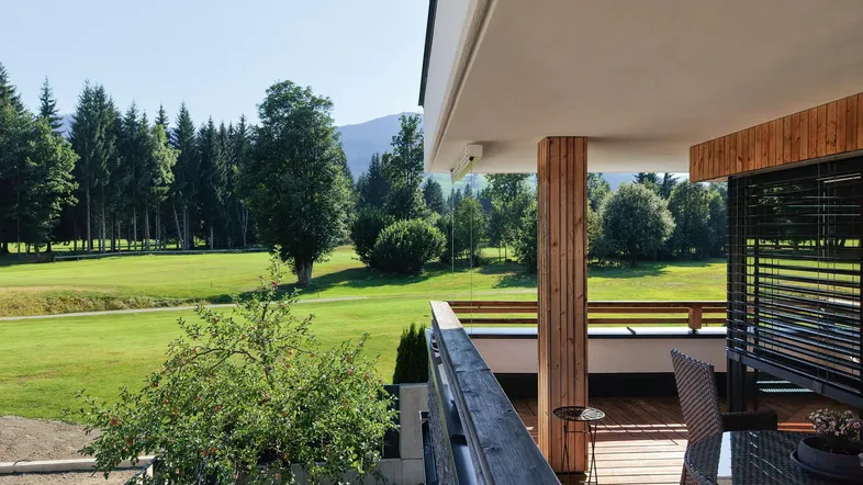 Moderner Balkon mit Holzboden und Sitzgelegenheiten, bietet einen weiten Blick ins Grüne und auf die Berge.
