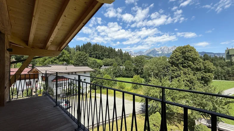 Geräumiger Balkon mit Holzboden und Geländer, bietet einen weiten Blick auf die Berge und grüne Landschaft.